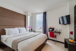 a hotel room with a large bed and a television at Life The One Makassar in Makassar