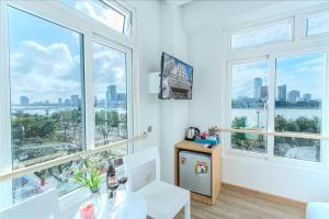 een witte kamer met grote ramen en een tafel en stoel bij Palmier Hotel - Art House Da Nang in Da Nang
