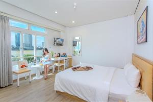 岘港Palmier Hotel - Art House Da Nang的坐在酒店房间桌子上的女人
