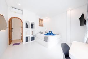 a white room with a bed and a tv at Bombora Surf Camp in Uluwatu