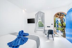 ein weißes Zimmer mit einem Bett und einem Stuhl in der Unterkunft Bombora Surf Camp in Uluwatu