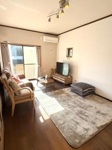 ein Wohnzimmer mit Sofa und Fernseher in der Unterkunft かみくまハウス in Kumamoto