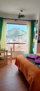 een slaapkamer met een bed en een tafel en een groot raam bij Jardín Andino Hostal in Copacabana