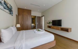 a bedroom with a large white bed and a flat screen tv at Aurora Serviced Apartments in Ho Chi Minh City