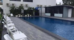 une piscine avec des chaises longues à côté d'un bâtiment dans l'établissement Chada Veranda Hotel, à Ban Si Than