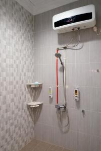 een douche met een rode slang in een badkamer bij ABC Homestay in Sentool