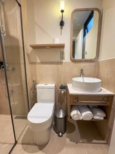 een badkamer met een toilet, een wastafel en een spiegel bij TWIN PALMS 'Beach House' - New surf front location in Thulusdhoo