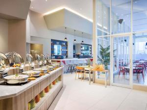 ein Restaurant mit einem Buffet mit Tischen und Stühlen in der Unterkunft Ibis Styles Jakarta Mangga Dua Square in Jakarta