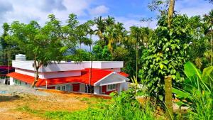 a red and white house with trees in the background at White Cloud Stay Attappadi in Agali