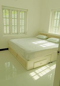 a bed in a white room with windows at White Cloud Stay Attappadi in Agali