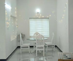 a dining room with a table and chairs and lights at White Cloud Stay Attappadi in Agali