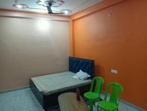 a small room with a bed and two green chairs at Om Mansion in Varanasi