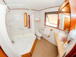 a bathroom with a tub and a toilet and a sink at Pao Pao Lodge Algarrobo in Algarrobo
