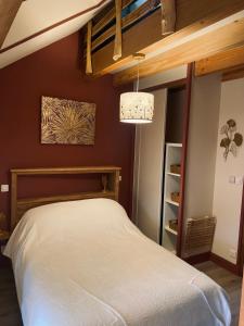 een slaapkamer met een wit bed en een kroonluchter bij La Longère des Oies in La Celle-sous-Gouzon