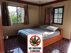 a bedroom with a bed with a no smoking sign on it at Tommy apartment in Koh Tao