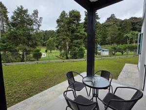a table and chairs on a porch with a view of a park at Teeview Homes 9A in Tanah Rata