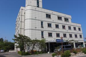een wit gebouw met een blauw bord ervoor bij Hotel Parkwood Incheon Airport in Incheon