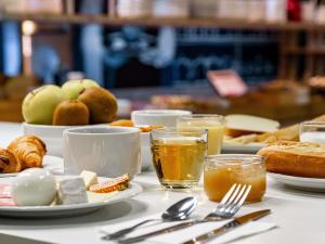 een tafel met borden eten en glazen sinaasappelsap bij ibis budget Marne la Vallée Pontault Combault in Pontault-Combault