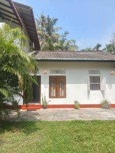 a white house with a palm tree in front of it at White Horizon 2 in Ahangama