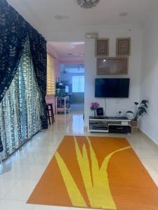 a living room with a tv and a rug at iLham Homestay in Kangar