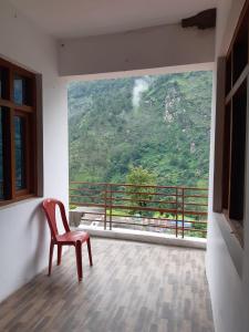 a red chair sitting on a balcony with a view at Hotel Arpit in Sonprayag