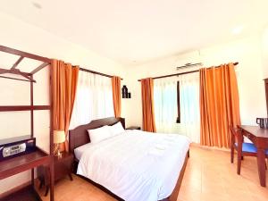 een slaapkamer met een bed, een bureau en een televisie bij Vang Vieng Ruby Villa Hotel in Vang Vieng