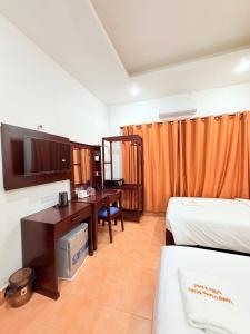 a room with two beds and a desk and a television at Vang Vieng Ruby Villa Hotel in Vang Vieng