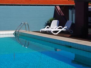 two white chairs sitting next to a swimming pool at Dongara Hotel Motel in Dongara