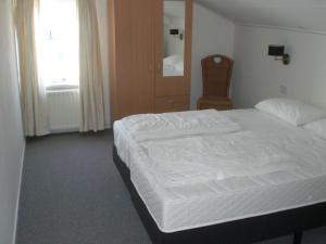 a bedroom with a white bed and a chair at Vakantieverblijf Uit en Thuis in Biggekerke