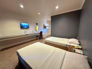 een hotelkamer met twee bedden en een bureau bij Rattana View in Phitsanulok +57 foto's