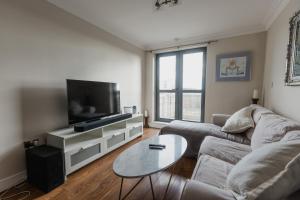 a living room with a couch and a tv and a table at Hullidays - King & Queen Ensuite in Hull