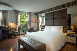 Schlafzimmer mit einem großen weißen Bett und einem Schreibtisch in der Unterkunft La Nueva Boutique Hotel Hanoi & Spa in Hanoi