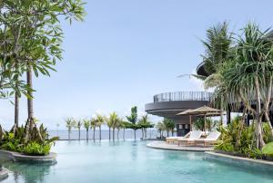 een zwembad met palmbomen en een gebouw bij Quenzo Beach Resort in Padangbai