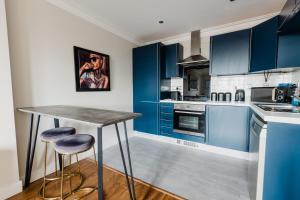 a blue kitchen with a table and two stools at Hullidays - King & Queen Ensuite in Hull