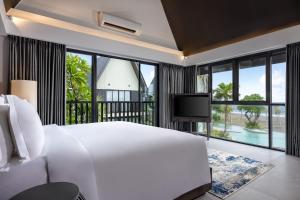 een slaapkamer met een groot wit bed en een flatscreen-tv bij Quenzo Beach Resort in Padangbai +29 foto's