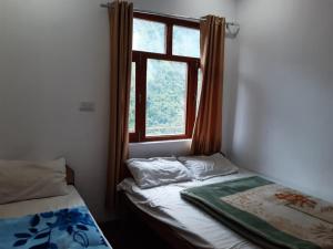 a room with two beds and a window at Hotel Arpit in Sonprayag