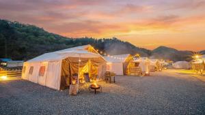 een groep tenten in een veld bij zonsondergang bij Gapyeong ILUGlamping in Gapyeong