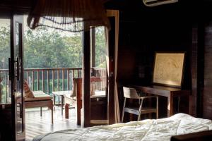 ein Schlafzimmer mit einem Balkon, einem Bett und einem Schreibtisch in der Unterkunft Alpha Wolf Lodge in Cemagi