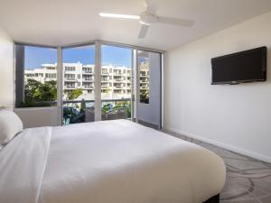 a bedroom with a large bed and a flat screen tv at Elysium Noosa Resort - MGallery Collection in Noosa Heads