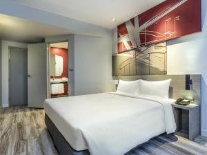 un grand lit blanc dans une chambre d'hôtel dans l'établissement ibis Bangkok IMPACT, à Nonthaburi