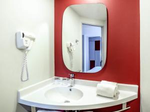 une salle de bains avec un lavabo blanc et un miroir dans l'établissement ibis Bangkok IMPACT, à Nonthaburi