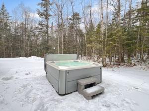 una vasca da bagno immersa nella neve nel bosco di The Mendon House Brought to you by GetAway Vacations a Killington