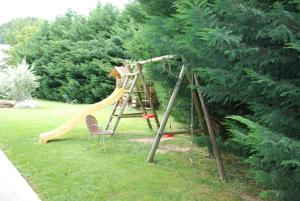 a playground with a slide and two chairs in a yard at Gardenhotel Premstaller in Bolzano