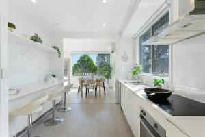 une cuisine avec des comptoirs blancs et une salle à manger dans l'établissement Self-Contained 3BR Upper-Level Unit Collaroy, à Collaroy