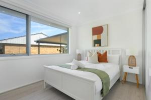 une chambre blanche avec un lit et une grande fenêtre dans l'établissement Self-Contained 3BR Upper-Level Unit Collaroy, à Collaroy