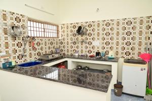 a kitchen with a counter and a tile wall at Cheenu Cottage in Yelagiri
