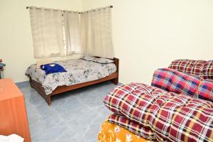 a bedroom with a bed and a couch and a window at Cheenu Cottage in Yelagiri