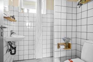 een wit betegelde badkamer met een toilet en een wastafel bij LF14127-Roslev-Kybehuse-127 in Roslev +29 foto's