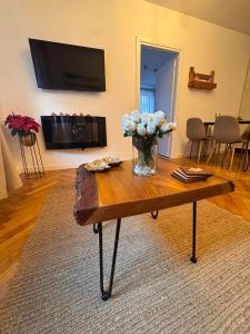 een vaas met bloemen op een houten tafel in een woonkamer bij Maple Lodge in Braşov