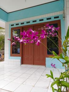 eine Haustür eines Hauses mit lila Blumen in der Unterkunft BATUKARAS Orchid Homestay in Batukaras